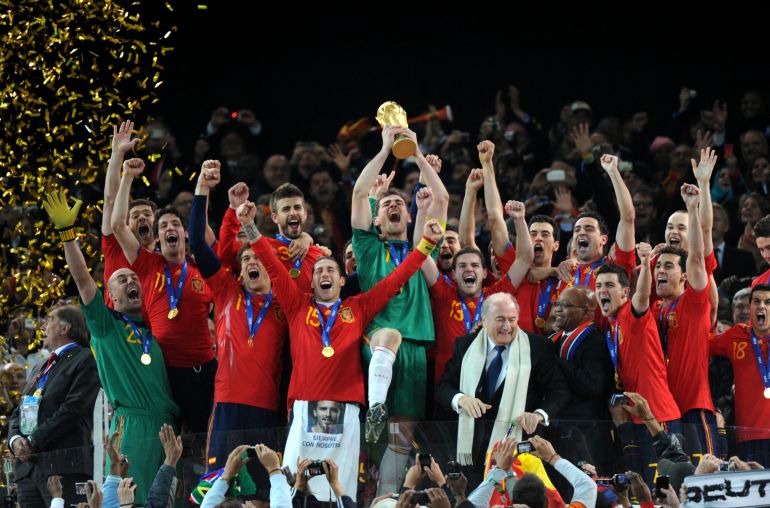 El portero español Iker Casillas (C) levanta el trofeo mientras los jugadores del equipo nacional de fútbol de España celebran con el presidente de la FIFA, Sepp Blatter (5thR) y el presidente de Sudáfrica, Jacob Zuma (4thR), ganando la final de la Copa Mundial de Fútbol 2010 Holanda contra España el 11 de julio de 2010 en el estadio Soccer City en Soweto, en los suburbios de Johannesburgo. NO PULSAR PARA MÓVIL / USO MÓVIL EXCLUSIVAMENTE DENTRO DEL ARTÍCULO EDITORIAL - AFP PHOTO / GABRIEL BOUYS (Foto de GABRIEL BOUYS / AFP)